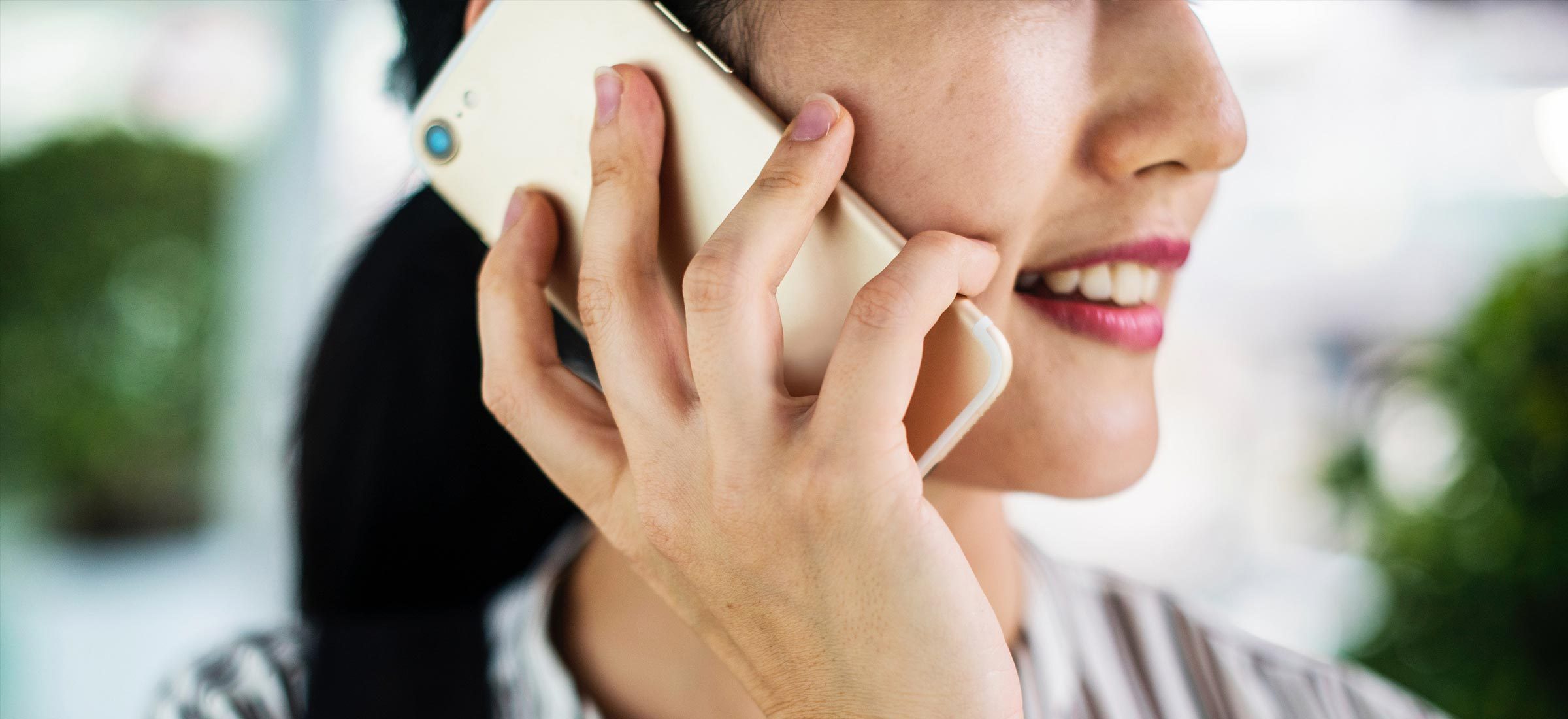 Ausschnitt eines Frauengesichts - Handy wird ans Ohr gehalten